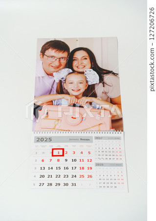 tear-off calendar with family photos on a white table.  127206726
