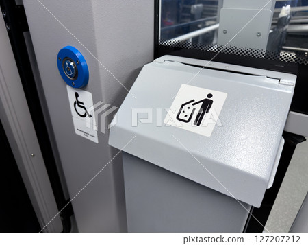 Interior of modern public transport with accessibility call button and trash bin, featuring clear signage for inclusive service and cleanliness in urban mobility infrastructure 127207212