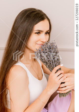 Woman in a white top and lilac skirt with lavender and relaxation in a soft cozy setting Woman in a white top and lilac skirt with lavender and relaxation in a soft cozy setting 127208019