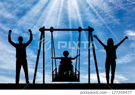 Silhouette of happy child is disabled in a wheelchair on an adaptive swing with mom and dad. have fun together 127208477