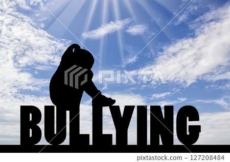 Silhouette of a sad and lonely girl child sitting on the word bullying against the sky Silhouette of a sad and lonely girl child sitting on the word bullying against the sky 127208484