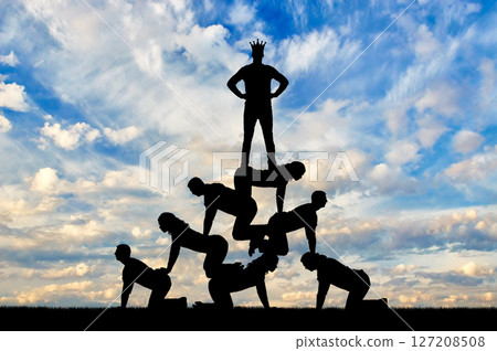 Silhouette narcissistic egoist man wearing a crown standing on humans Silhouette narcissistic egoist man wearing a crown standing on humans 127208508