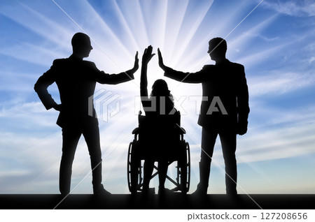 Empowering Inclusion: Silhouetted Businesspeople High-Five a Person in a Wheelchair Against a Bright Sky 127208656
