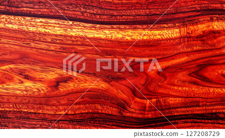 wood texture background, mahogany wood texture, showcasing its rich reddish brown color and seamless grain pattern. This luxurious wood surface features elegant, swirling natural lines 127208729