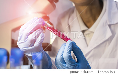 Scientist doing chemical experiment in laboratory with flask of liquid. Concept of science research, chemistry study and laboratory investigation 127209194