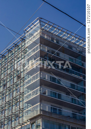 Modern office building with glass facade and balconies under clear blue sky. High quality photo 127210107