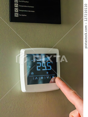 Thermostat close-up with a finger adjusting temperature. High quality photo 127210110