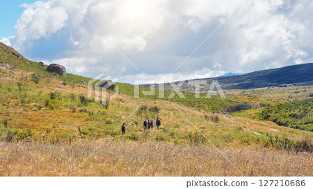 Group of hikers going through sun lit valley during descent from pic Boby in Andringitra national park. View from behind, no persons recoginizable Group of hikers going through sun lit valley during descent from pic Boby in Andringitra national park. View from behind, no persons recoginizable 127210686