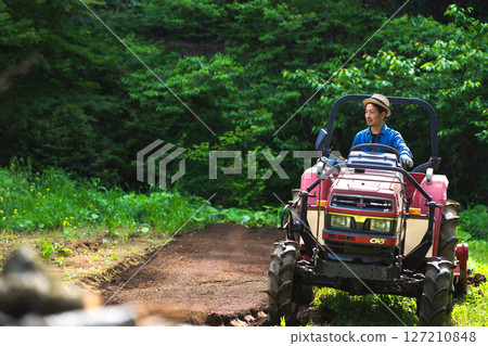 年輕人用拖拉機耕地 127210848