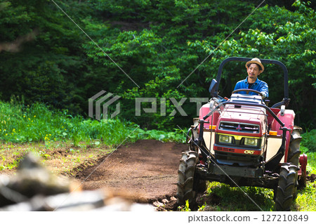 年輕人用拖拉機耕地 年輕人用拖拉機耕地 127210849