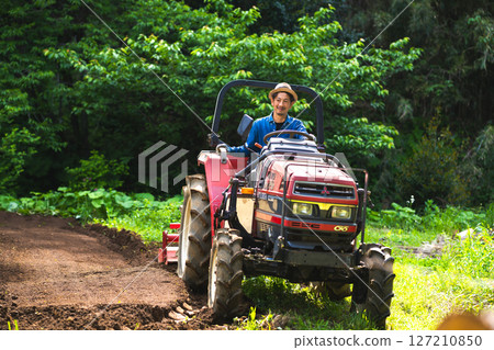 年輕人用拖拉機耕地 127210850