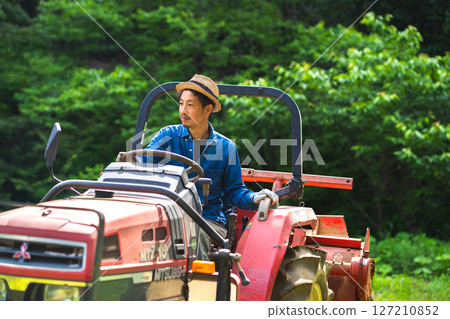 Young man plowing the field with a tractor 127210852
