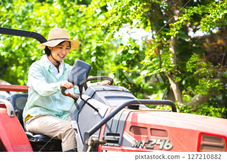 Woman plowing the field with a tractor 127210882