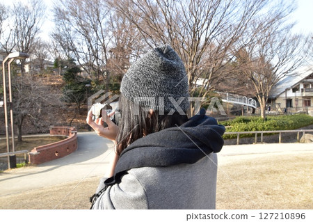 A woman eating rice balls and holding a camera 127210896