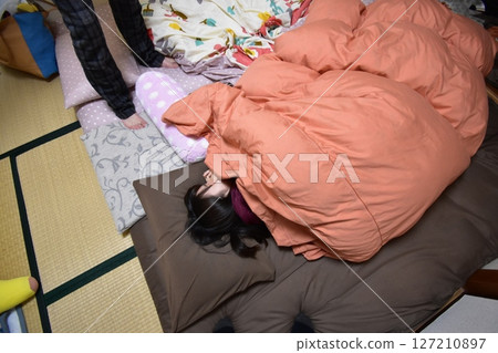 一名女子在飯店裡裹著被褥揉著眼睛 一名女子在飯店裡裹著被褥揉著眼睛 127210897