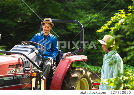 一個男人騎著拖拉機，一個女人看著他 127210930