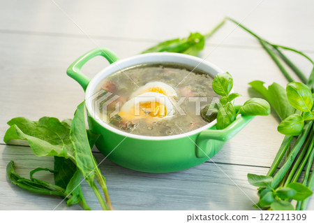 Ukrainian dish borscht with greens and egg on light wooden table Ukrainian dish borscht with greens and egg on light wooden table 127211309