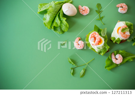 Sandwich with egg and shrimp on green background from above 127211313