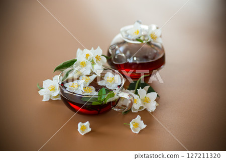Natural green tea with jasmine petals on a brown background Natural green tea with jasmine petals on a brown background 127211320