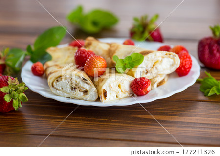 Pancakes with cottage cheese and strawberries on a wooden table 127211326