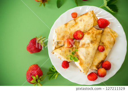 Pancakes with cottage cheese and strawberries on a green background 127211329