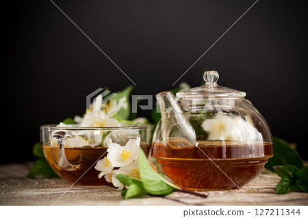 Jasmine flowers and tea in a cup on a black background Jasmine flowers and tea in a cup on a black background 127211344