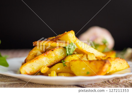 Crispy potatoes with herbs and garlic aroma on a black background Crispy potatoes with herbs and garlic aroma on a black background 127211353