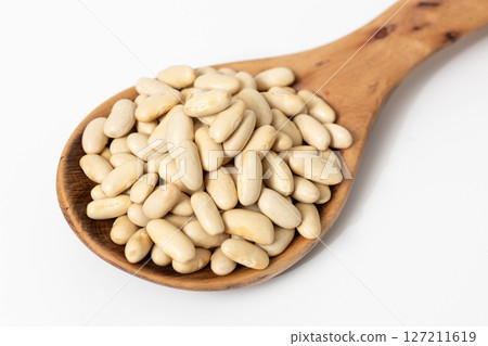 Close-up of a wooden spoon with raw cannellini beans isolated on white background Close-up of a wooden spoon with raw cannellini beans isolated on white background 127211619