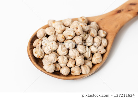 Close-up of a wooden spoon with raw chickpeas isolated on white background 127211624