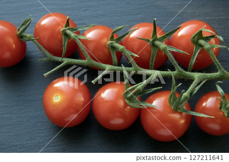 Red cherry tomatoes on a branch on gray background. Red cherry tomatoes on a branch on gray background. 127211641