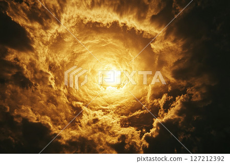 Dark thick clouds in a vortex. The sun at the end of a cloud tunnel. Dark thick clouds in a vortex. The sun at the end of a cloud tunnel. 127212392