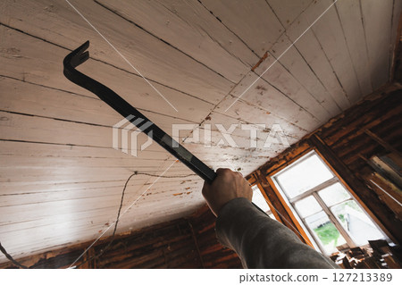 A hand gripping a crowbar in an indoor construction or renovation setting 127213389