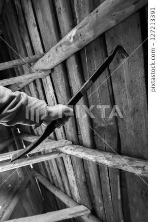 Person gripping a metal prying tool inside a weathered wooden structure 127213391