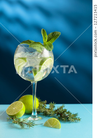 Cocktails gin and tonic with ice and lime slices on a blue background. 127213415