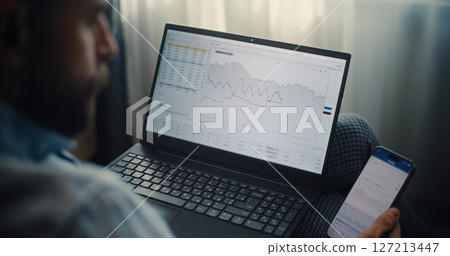Close Up of Financial Expert Working on Smartphone and Laptop in Online Trading App 127213447
