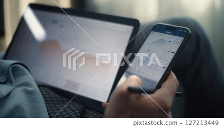 Close Up of Businessman Working on Smartphone and Tablet Displaying Real-Time Stocks in Trading App Close Up of Businessman Working on Smartphone and Tablet Displaying Real-Time Stocks in Trading App 127213449
