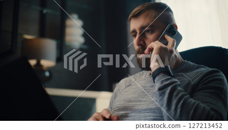 Financial Analyst Having Phone Call, Working on Laptop, Monitoring Exchange Market Charts 127213452