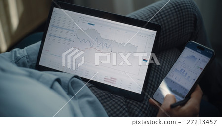 Close Up of Stock Exchange Trader Using Tablet and Smartphone, Analyzing Real-Time Stocks in Trading App Close Up of Stock Exchange Trader Using Tablet and Smartphone, Analyzing Real-Time Stocks in Trading App 127213457