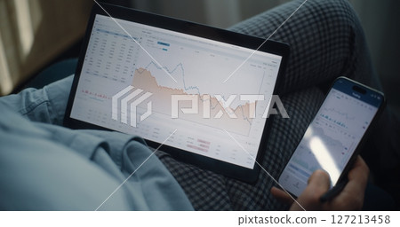 Close Up of Stock Exchange Trader Using Tablet and Smartphone, Analyzing Real-Time Stocks in Trading App Close Up of Stock Exchange Trader Using Tablet and Smartphone, Analyzing Real-Time Stocks in Trading App 127213458