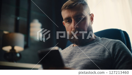 Close Up of Financial Expert Working on Smartphone, Monitoring Real-Time Stocks in Comfortable Home Office 127213460