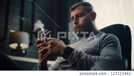 Stock Exchange Trader Monitoring Exchange Market Charts Using Smartphone, Drinking Coffee 127213462