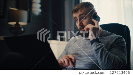 Professional Stock Exchange Trader Monitoring Real-Time Stocks Using Laptop, Talking on Cellphone 127213466