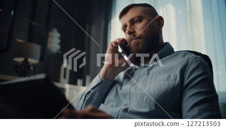 Stock Exchange Trader Talking on Cellphone, Monitoring Real-Time Stocks Using Tablet 127213503
