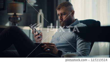 Stock Exchange Trader Monitoring Exchange Market Charts Using Smartphone and Tablet Computer 127213514