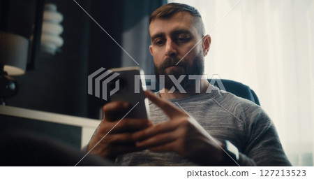Stock Exchange Trader Analyzing Exchange Market Charts Using Smartphone in Cozy Office Stock Exchange Trader Analyzing Exchange Market Charts Using Smartphone in Cozy Office 127213523