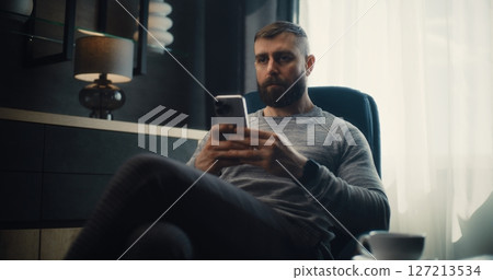 Financial Analyst Working on Smartphone, Analyzing Exchange Market Charts in Comfortable Office 127213534