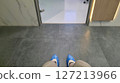 Waiting at a clinic entrance. First-person view of feet in blue shoe covers. Healthcare, medical visit concept. Clean and sterile environment. 127213966