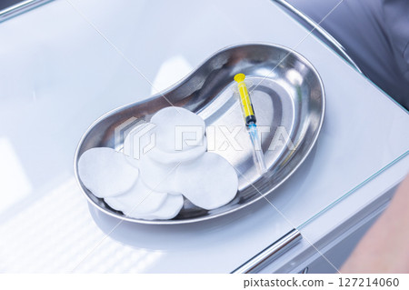 Sterile Stainless Steel Tray Featuring Cotton Pads and A Syringe, Typically Used In Medical And Healthcare Settings For Various Procedures And Treatments Sterile Stainless Steel Tray Featuring Cotton Pads and A Syringe, Typically Used In Medical And Healthcare Settings For Various Procedures And Treatments 127214060