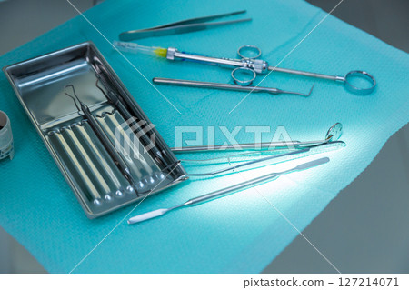 A Collection of Dental Instruments on a Light Blue Surface in a Clean Medical Environment Ready for Clinical Procedures and Patient Care with High-Quality Surgical Tools Visible 127214071