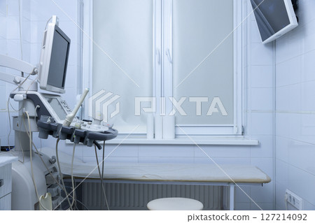 Modern Medical Sonography Room Featuring Ultrasound Equipment and Treatment Table Surrounded by Clean, White Tiles and Natural Light from the Window Modern Medical Sonography Room Featuring Ultrasound Equipment and Treatment Table Surrounded by Clean, White Tiles and Natural Light from the Window 127214092